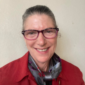 UCLA Professor Brenda Freshman wearing eyeglassess with her hair pulled back from her face as she wears a red blazer and grey neck scarf