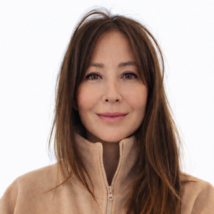 headshot of UCLA Executive MPH faculty member Dr. Sophie Snyder. She is wearing a light beige zip-up sweater. She has long straight brown hair hanging over her left shoulder.