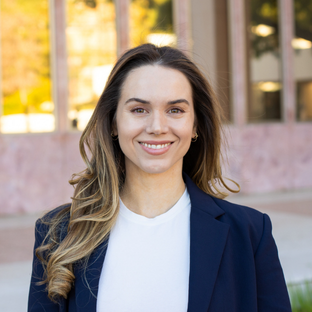 headshot of UCLA Executive MPH graduate Emily Brown. She has long straight light brown hair and she is wearing dark blue blazer over a white top