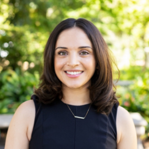 EMPH Student Maite Medina stands outside near a green-leafed tree. She wears a sleeveless black top and a silver necklace.