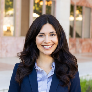 headshot of UCLA Executive MPH graduate Marina Martinez. She has long dark brown hair and she wears a navy blue blazer over a light blue button up collared shirt.