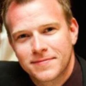 Close-up headshot of D'Artagnan DeBow, MD, MBA, a UCLA Fielding School of Public Health Executive Master of Public Health student. He has short reddish-blonde hair and light eyes, posing with a slight smile and wearing a dark suit jacket.