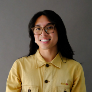 headshot of UCLA EMPH student, class of 2028, Joshua Teodoro. They have long straight black hair and are wearing red eyeglasses and a light yellow collared button-up shirt