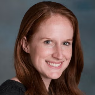 headshot of UCLA Biostatistics lecturer in the UCLA EMPH program. She is smiling and has long straight red hair and wear a black shirt.
