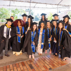 group shot of UCLA EMPH graduates on commencement day 2026. They are all wearing caps and gowns and regalia.