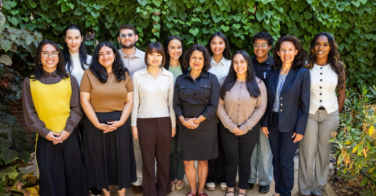group photo of the EMPH Class of 2028, taken at Orientation on the UCLA Campus. They stand together in professional attire looking at the camera, smiling. The backdrop is a vine covered wall.
