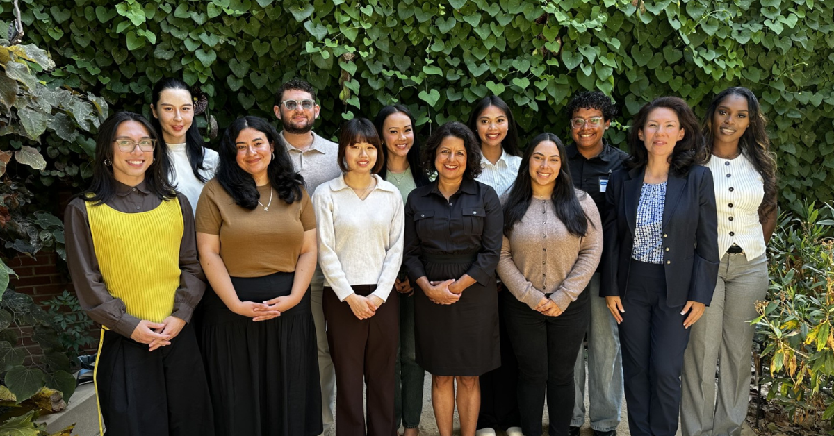 group photo of the EMPH Class of 2028, taken at Orientation on the UCLA Campus. They stand together in professional attire looking at the camera, smiling. The backdrop is a vine covered wall.