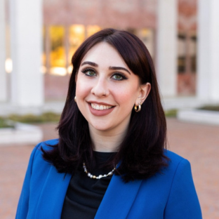headshot of UCLA EMPH grad Erica Cirineo. She wears a royal blue blazer over a black top.