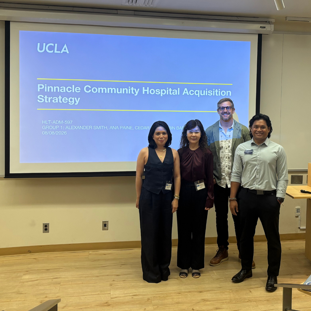 Four UCLA MHA students stand inside a lecture hall in the front of the room as they are about to give their case presentation during MHA Immersion, Summer 2026.